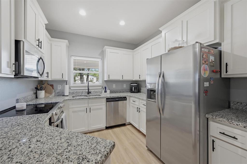 501 Bonham Street Tom Bean, TX 75491 - Photo 12 of 40 a kitchen with stainless steel appliances granite countertop a refrigerator a sink a stove and white cabinets
