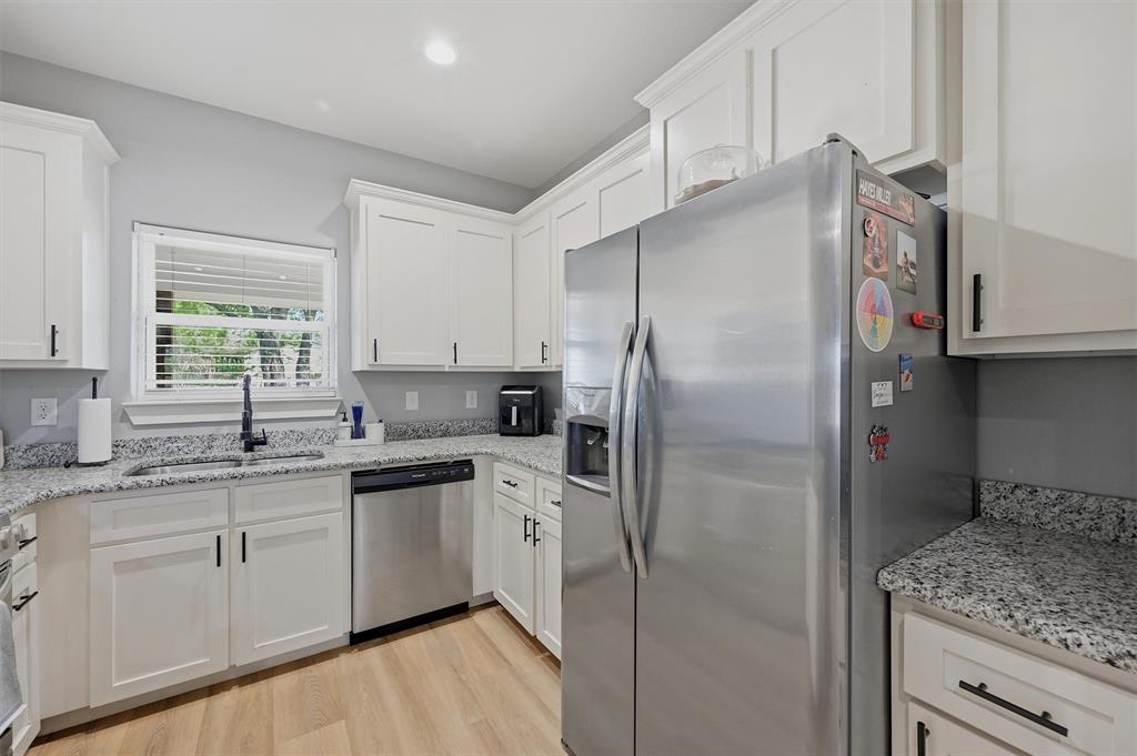 501 Bonham Street Tom Bean, TX 75491 - Photo 14 of 40 a kitchen with stainless steel appliances granite countertop a refrigerator a sink and white cabinets