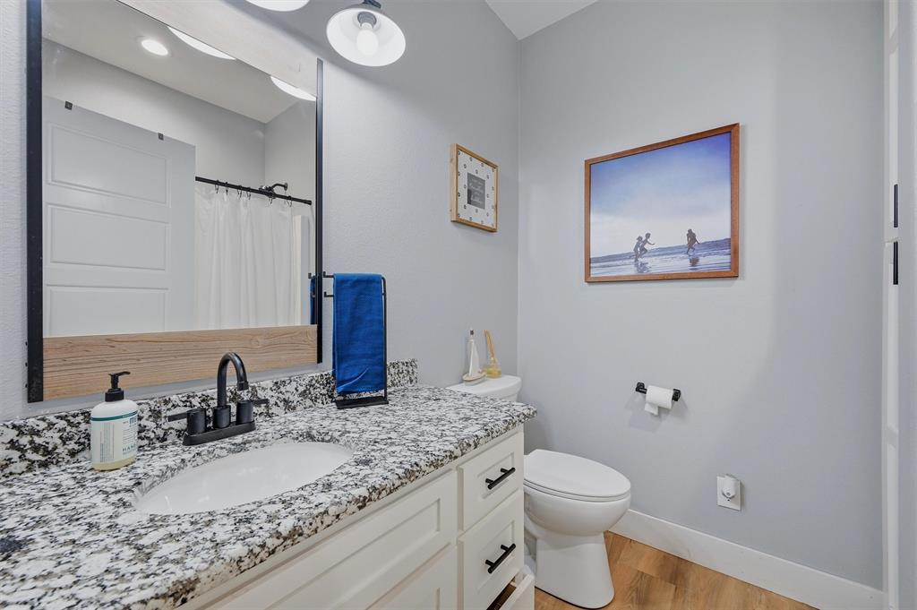 501 Bonham Street Tom Bean, TX 75491 - Photo 30 of 40 a bathroom with a granite countertop sink mirror vanity and toilet