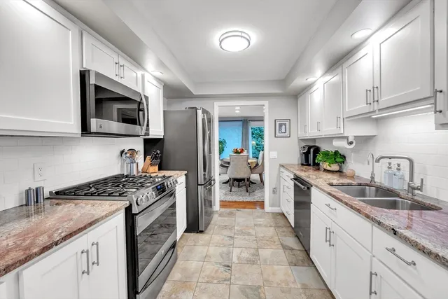 a kitchen with stainless steel appliances granite countertop a sink stove microwave and refrigerator