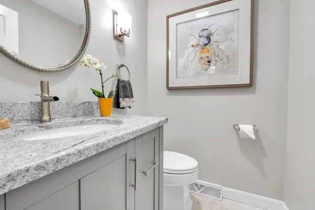 a bathroom with a granite countertop sink a mirror and a toilet