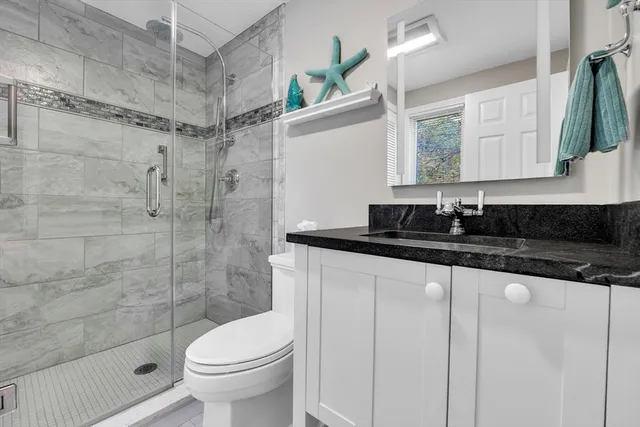 a bathroom with a granite countertop sink toilet and shower