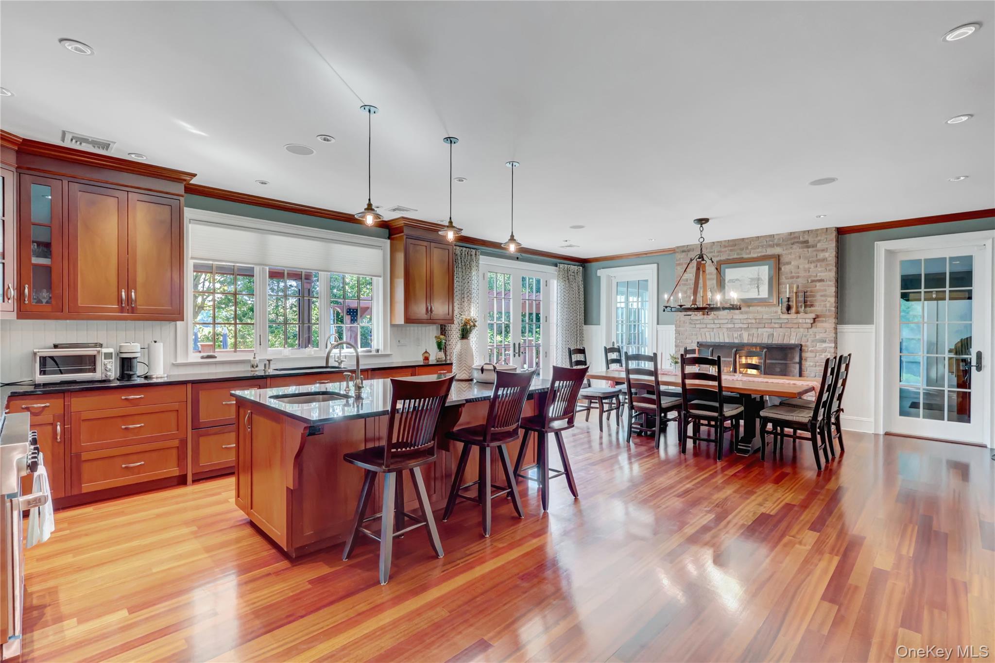 63 Dyke Road Setauket, NY 11733 - Photo 10 of 49 Kitchen with a kitchen breakfast bar, pendant lighting, glass insert cabinets, light wood-style flooring, and crown molding