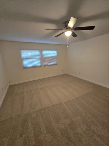 an empty room with ceiling fan and window