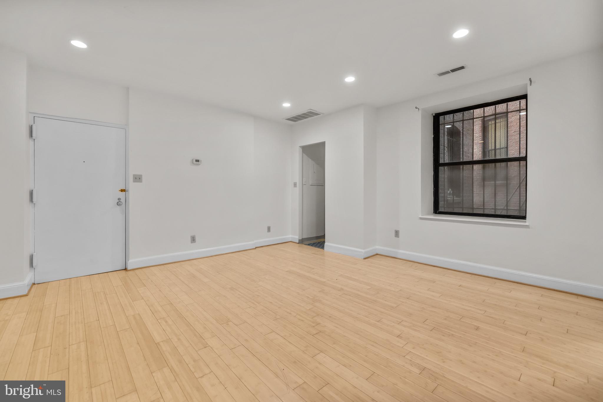 1115 12th Street Northwest, Unit 104 Washington, DC 20005 - Photo 5 of 25 a view of an empty room with wooden floor and a window