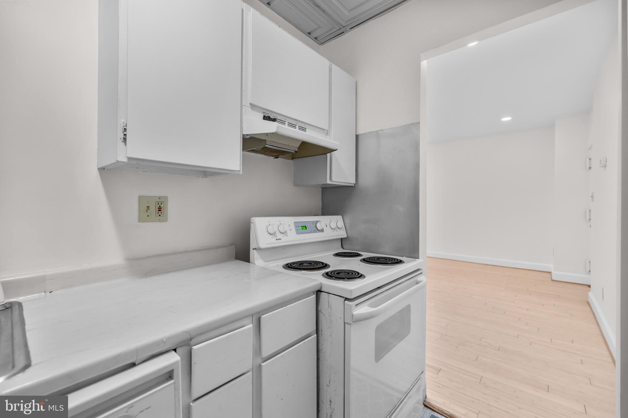 1115 12th Street Northwest, Unit 104 Washington, DC 20005 - Photo 10 of 25 a kitchen with stainless steel appliances a white stove top oven and white cabinets