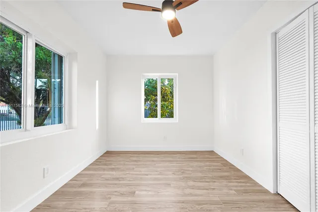 a view of an empty room with wooden floor and windows