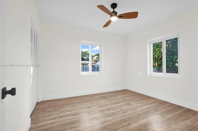 an empty room with a window and a ceiling fan