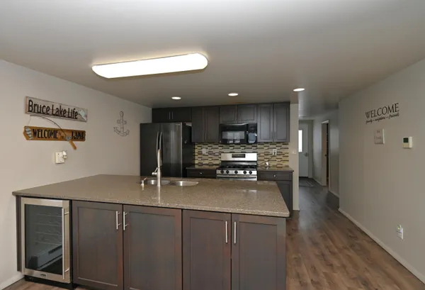 a kitchen with stainless steel appliances granite countertop a sink a stove a refrigerator cabinets and a dining table