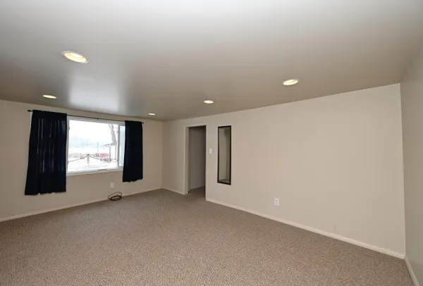 a view of an empty room with a window and fireplace