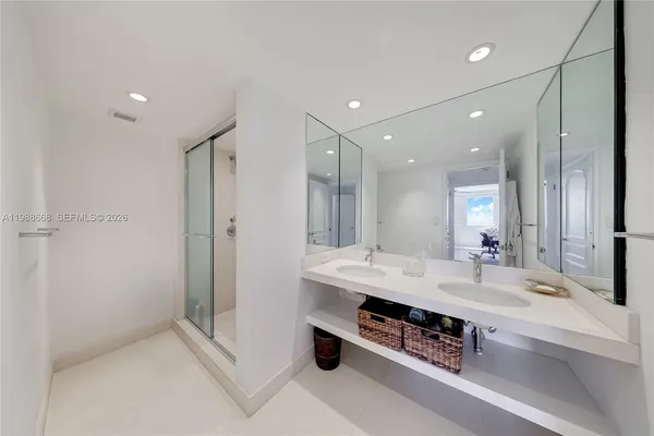 a bathroom with a double vanity sink a large mirror and shower