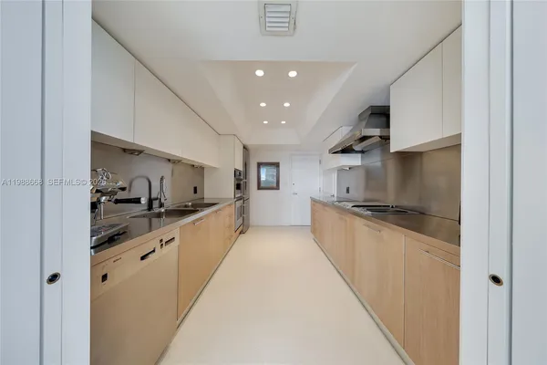 a large kitchen with stainless steel appliances a sink and cabinets