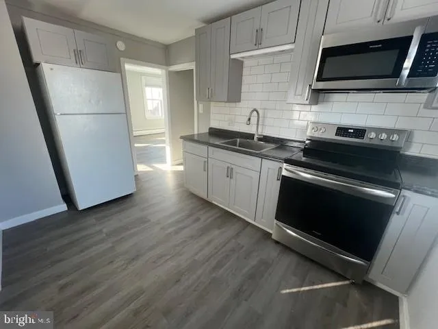 a kitchen with stainless steel appliances a stove microwave and sink