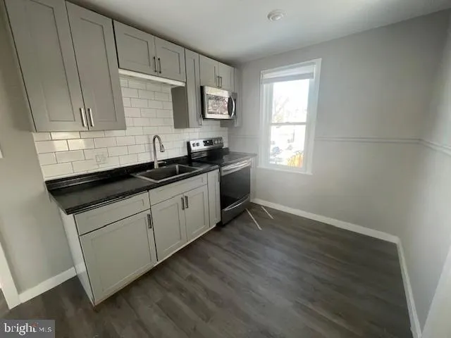 a kitchen with granite countertop white cabinets sink and window