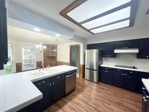 a large kitchen with stainless steel appliances granite countertop a sink stove and wooden cabinets