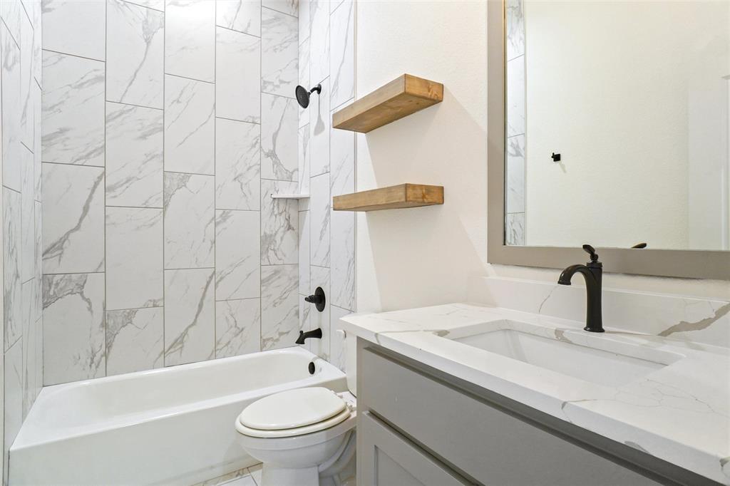 107 South 6th Street Godley, TX 76044 - Photo 17 of 21 a bathroom with a granite countertop sink a toilet and bathtub