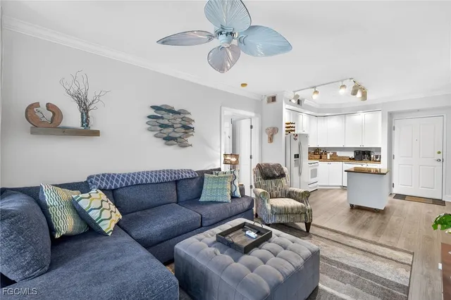 a living room with furniture kitchen view and a chandelier