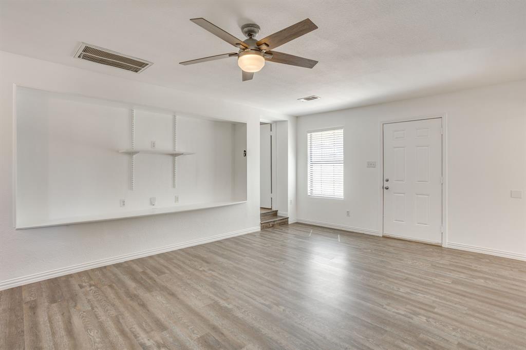 6940 Hatch Road Fort Worth, TX 76135 - Photo 17 of 40 Wood-finish flooring throughout, ceiling fan with integrated lighting, built-in shelving, white paneled door, and window with blinds