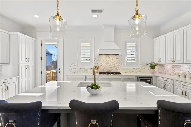 a kitchen with stainless steel appliances granite countertop a stove top oven a sink a dining table and chairs with wooden floor