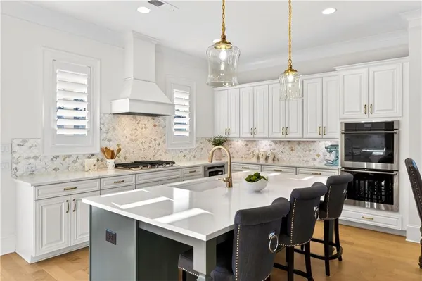 a kitchen with stainless steel appliances granite countertop a stove top oven a sink a dining table and chairs with wooden floor