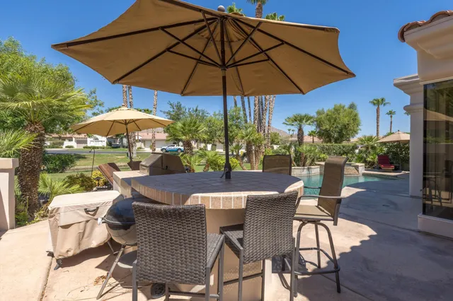 a view of a patio with table and chairs under an umbrella