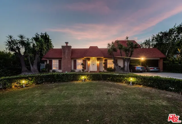 a front view of a house with a garden and a car