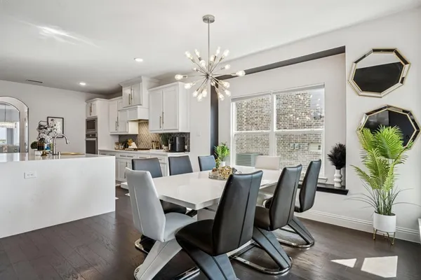 a dining room with furniture a chandelier and wooden floor