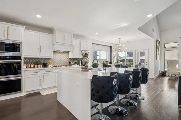 a kitchen with stainless steel appliances granite countertop a refrigerator a stove a sink dishwasher and white cabinets with wooden floor