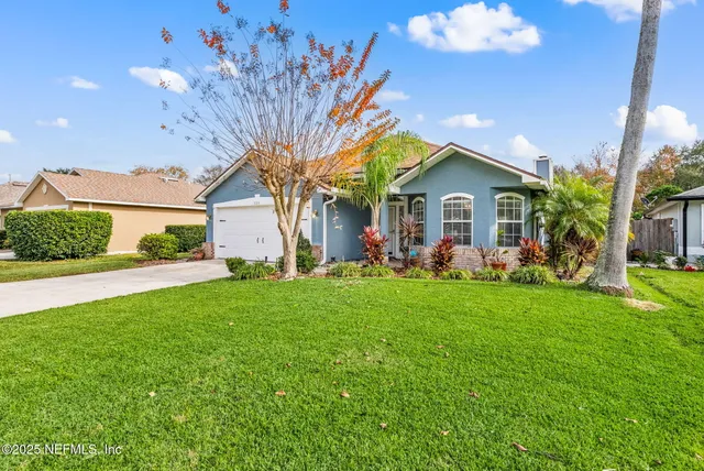 a view of a house with a big yard plants and large trees