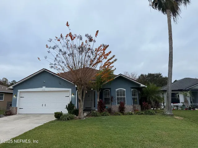 a front view of a house with a garden and trees