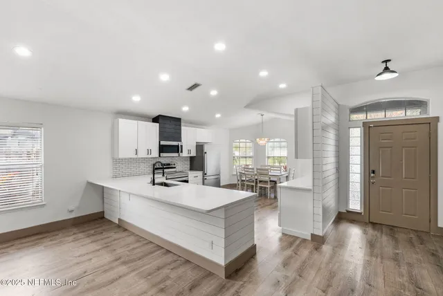 a room with stainless steel appliances kitchen island granite countertop a sink and cabinets