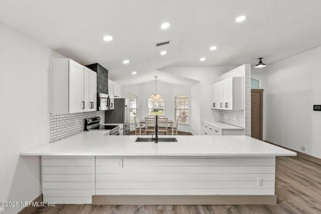 a view of kitchen with kitchen island stainless steel appliances sink and living room