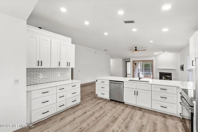 a kitchen with white cabinets and sink