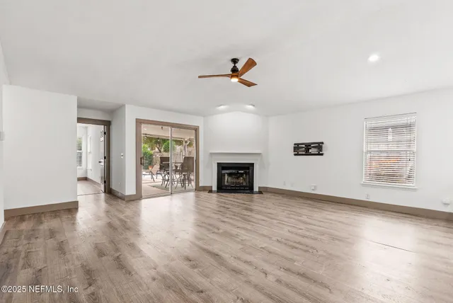 an empty room with wooden floor fireplace and windows