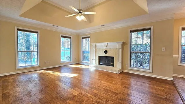an empty room with windows fireplace and wooden floor