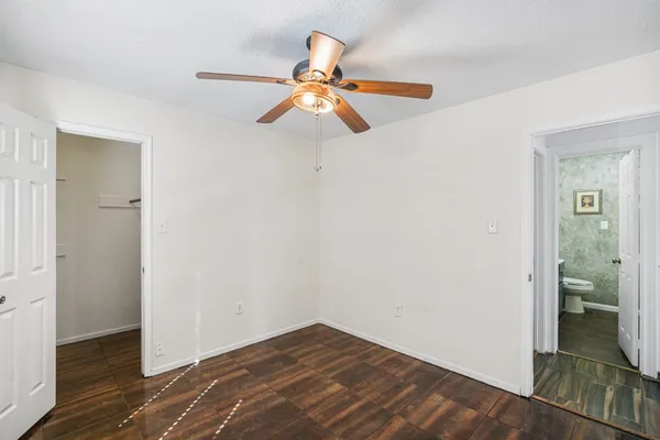 an empty room with wooden floor fan and windows