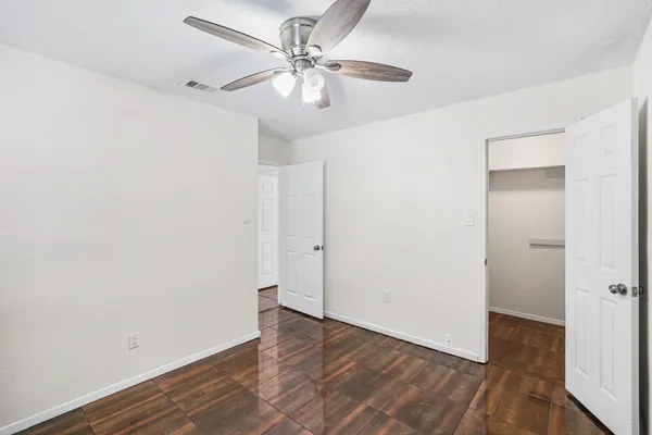 an empty room with wooden floor fan and windows