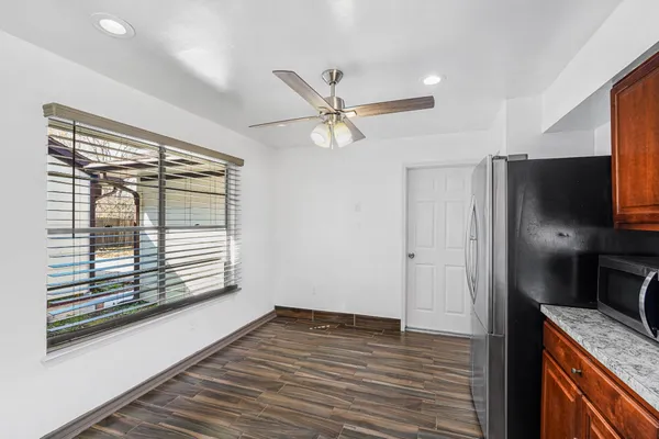 an empty room with wooden floor a ceiling fan and a window