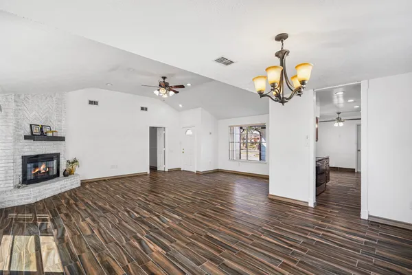 a view of a livingroom with a fireplace a chandelier and wooden floor