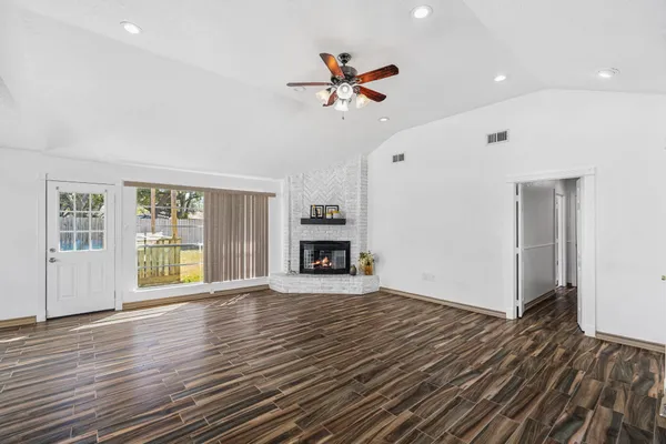 a view of an empty room with wooden floor fireplace and a window