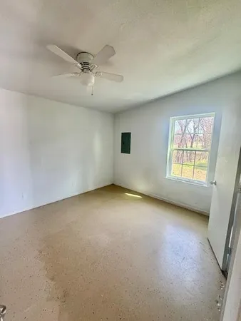 an empty room with windows and fan
