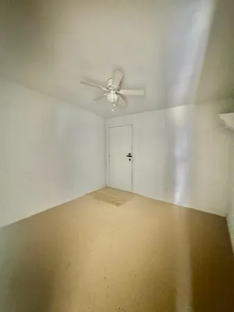 an empty room with a chandelier fan and windows