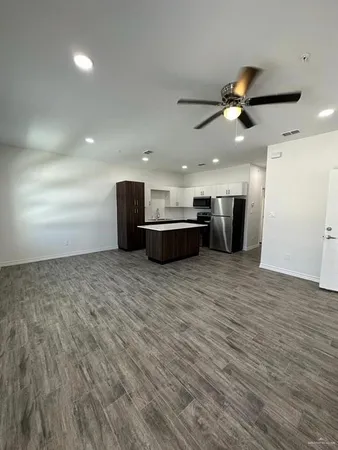 a view of a big room with wooden floor and windows