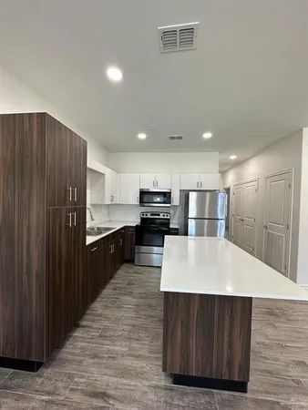 a large kitchen with stainless steel appliances a large counter top and wooden cabinets