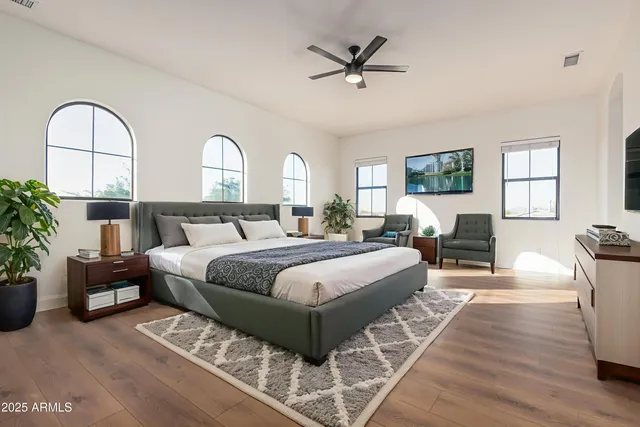 a spacious bedroom with a bed a couch and potted plants on the dresser