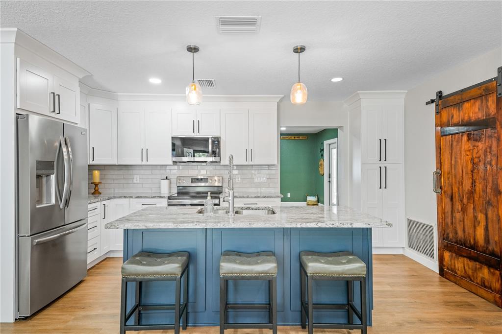9653 Golden Grove Street Seminole, FL 33772 - Photo 2 of 29 a kitchen with kitchen island granite countertop a refrigerator a sink dishwasher a oven a dining table and chairs with wooden floor