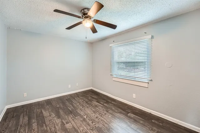 an empty room with a window and a fan