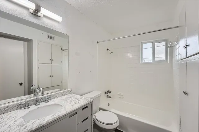 a bathroom with a granite countertop sink toilet a large mirror a bathtub and shower