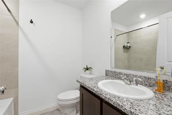a bathroom with a granite countertop sink a toilet and a mirror