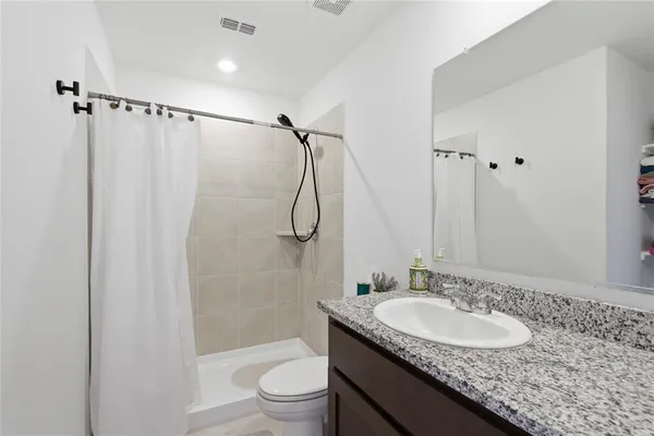 a bathroom with a granite countertop sink toilet and shower